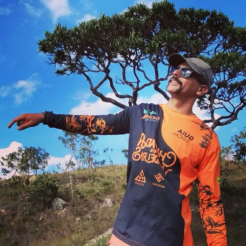 Guia da Nava Expeditions sorrindo em frente a uma cachoeira na Chapada dos Veadeiros.